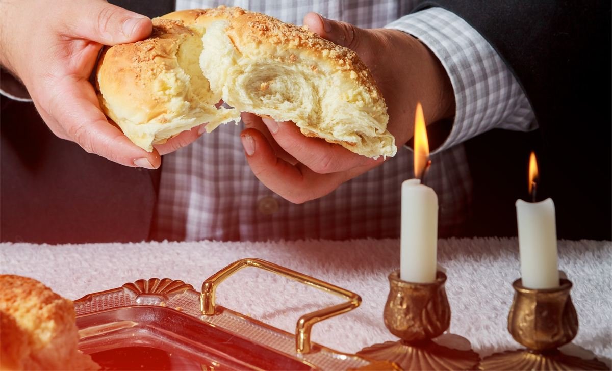 ידיים קורעות חלה, ולידן שני נרות שבת דולקים