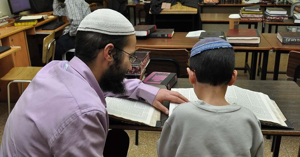 חונך וילד יושבים זה לצד זה, וכל אחד מהם מול ספר פתוח